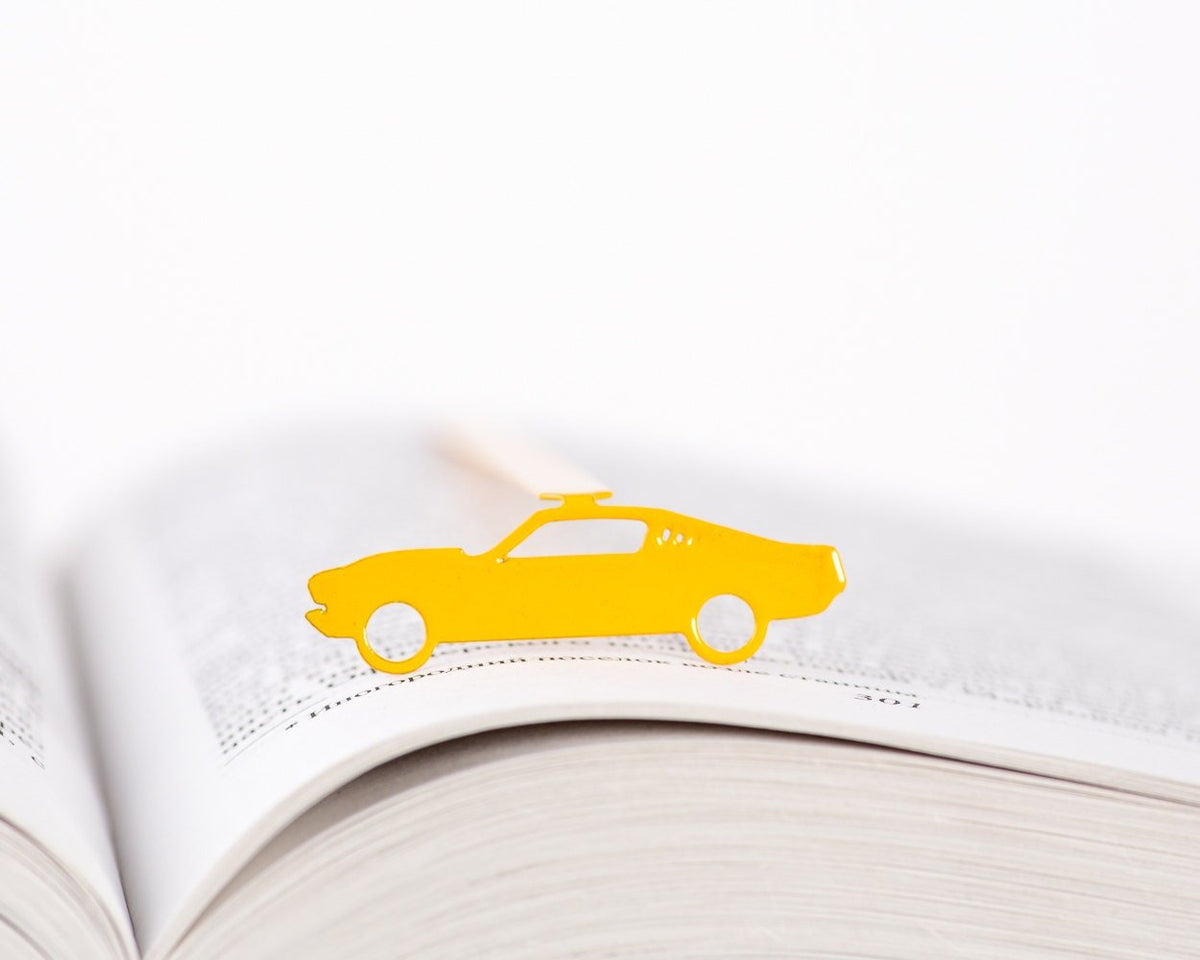 Yellow Muscle Car metal bookmark in gold marking a page in an open book