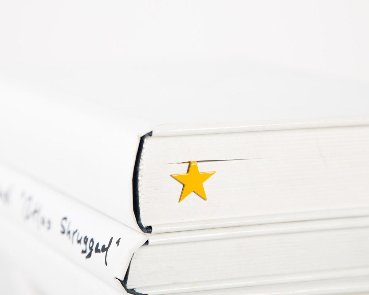 Yellow Star metal bookmark in gold in a closed book, only its top showing above the pages