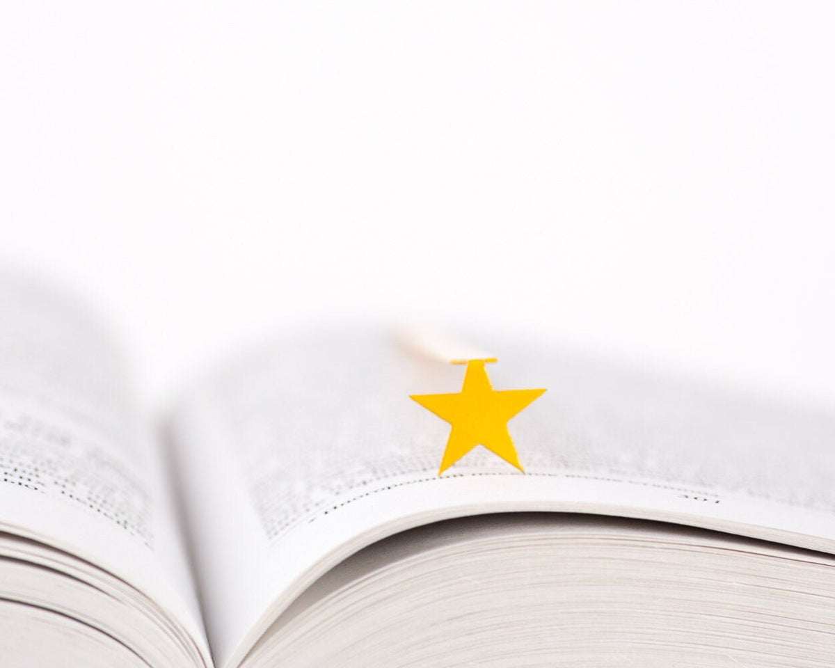 Yellow Star metal bookmark in gold resting on the pages of an open book