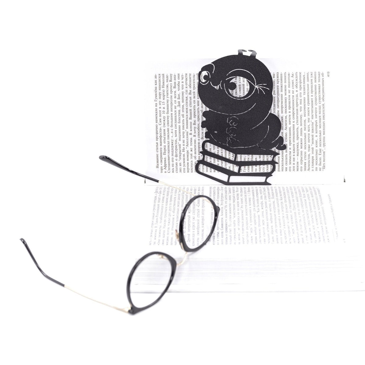 Bookworm metal bookmark in green resting on the pages of an open book