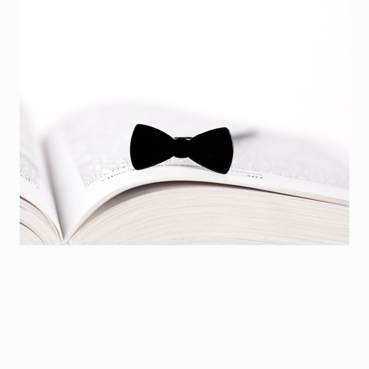 Bow Tie metal bookmark resting on the pages of an open book
