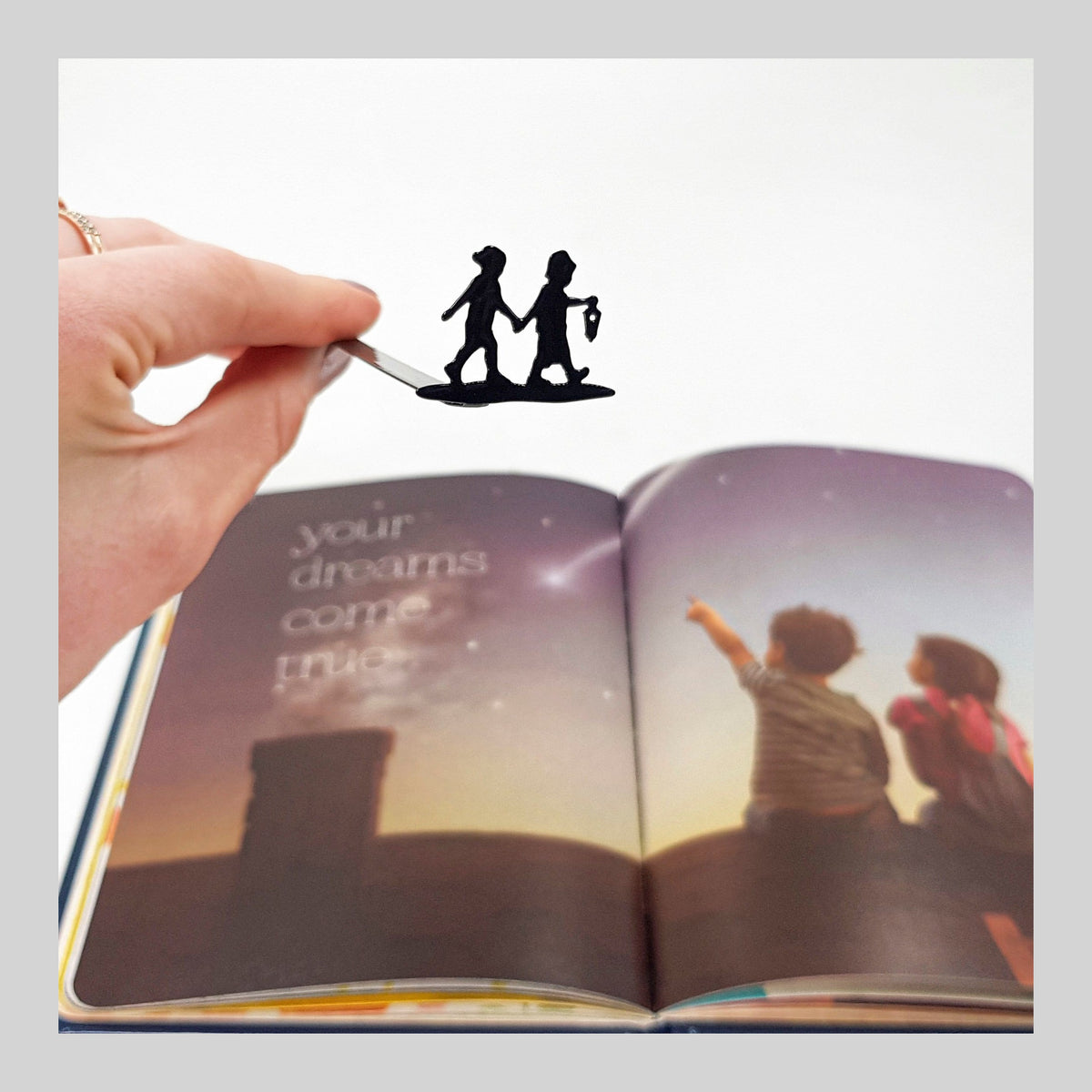 Boy and Girl metal bookmark marking a page in an illustrated book