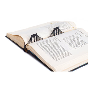 Brooklyn Bridge metal bookmark resting on the pages of an open book