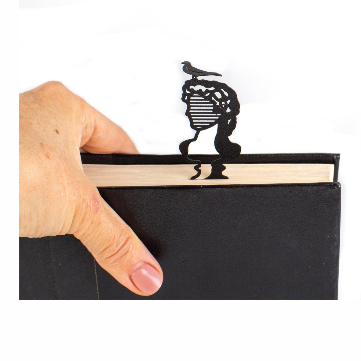 Bust to a Famous Reader metal bookmark held in a hand above an open book