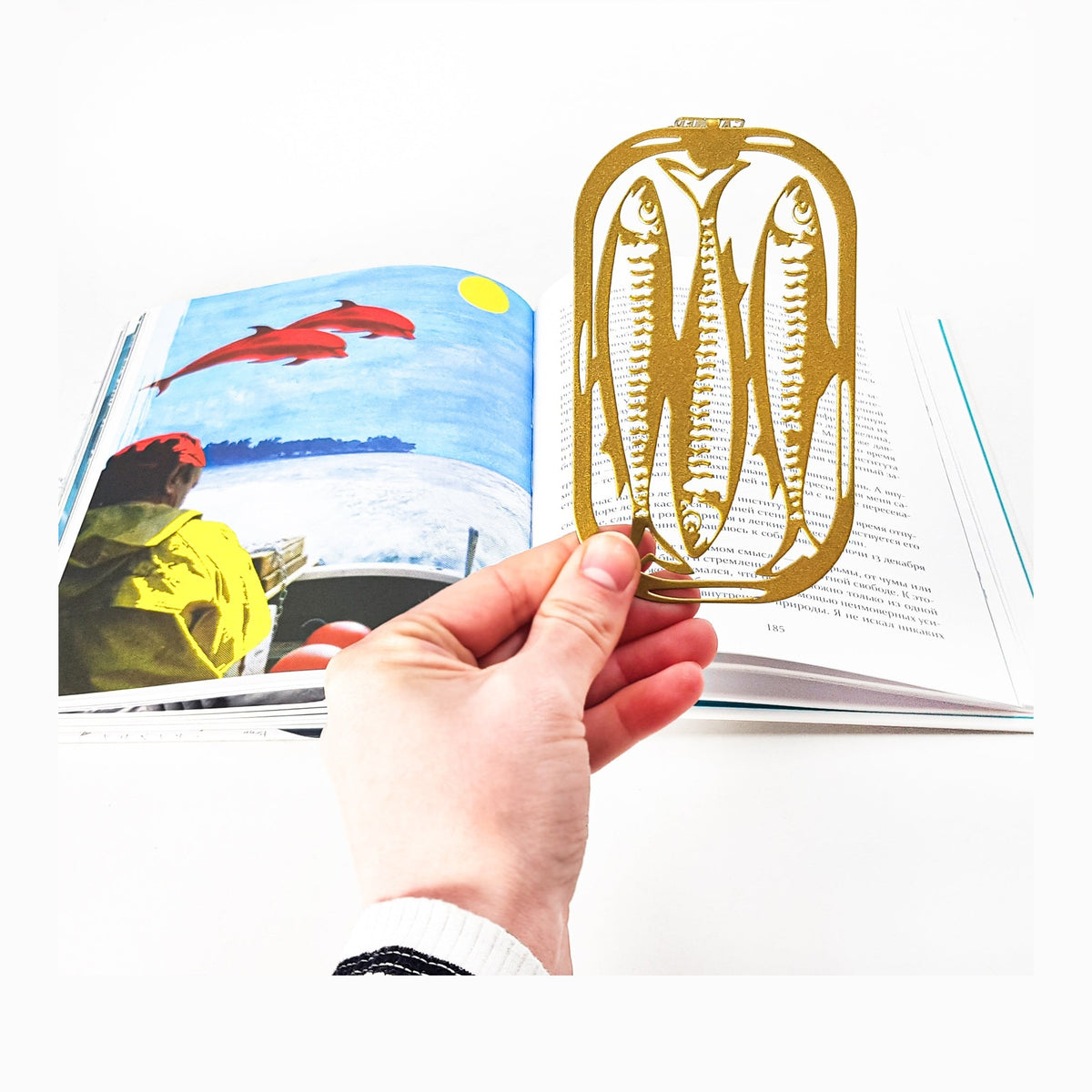 Canned Classics metal bookmark in gold marking a page in an illustrated book