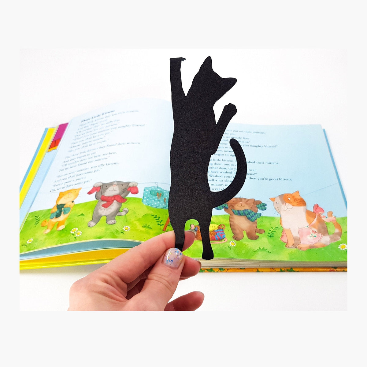 Cat Got Stuck metal bookmark marking a page in an illustrated book