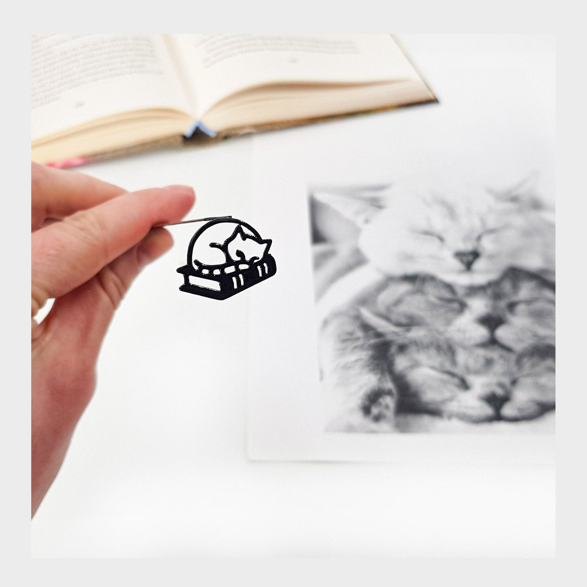 Cat Naps and Page Turns metal bookmark marking a page in an illustrated book