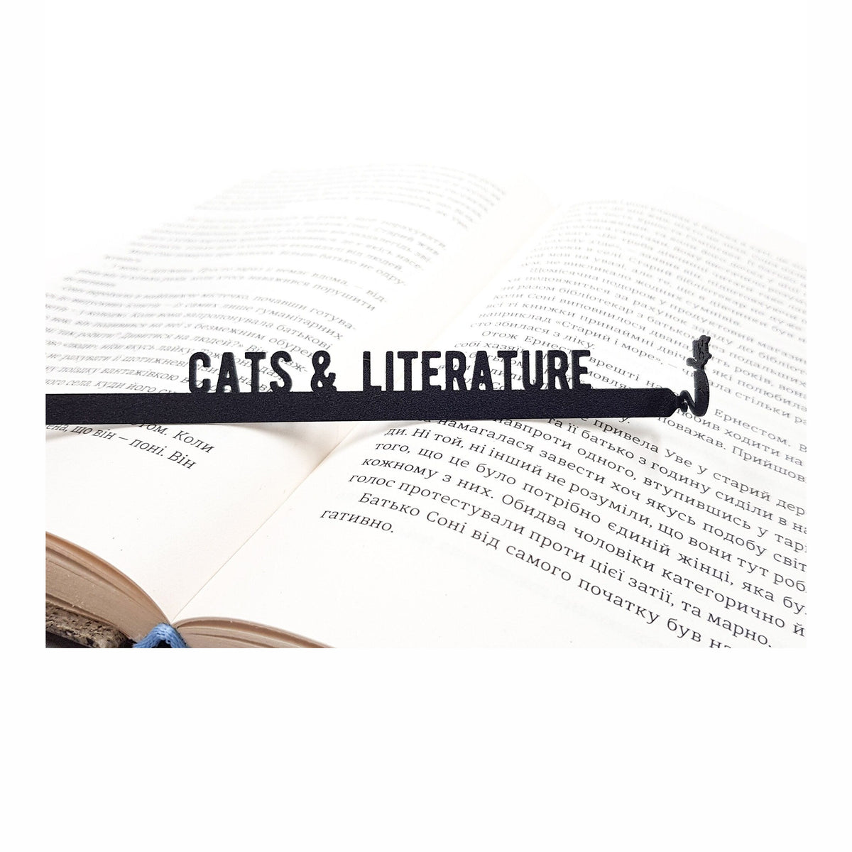 Cats and Literature metal bookmark resting on the pages of an open book
