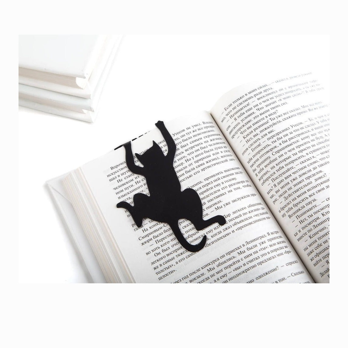 Cat's Library metal bookmark resting on the pages of an open book