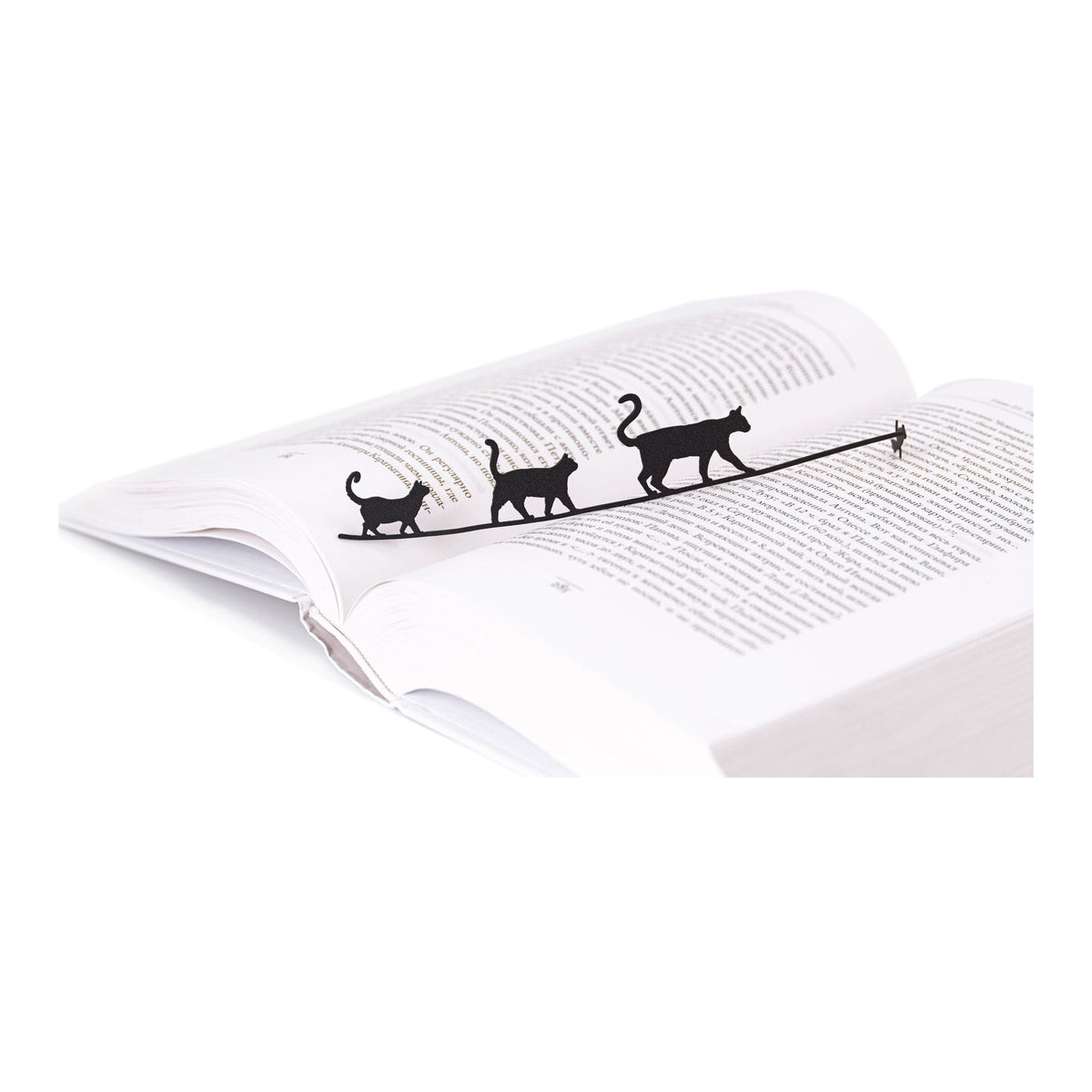 Cats Tightrope Walkers metal bookmark resting on the pages of an open book