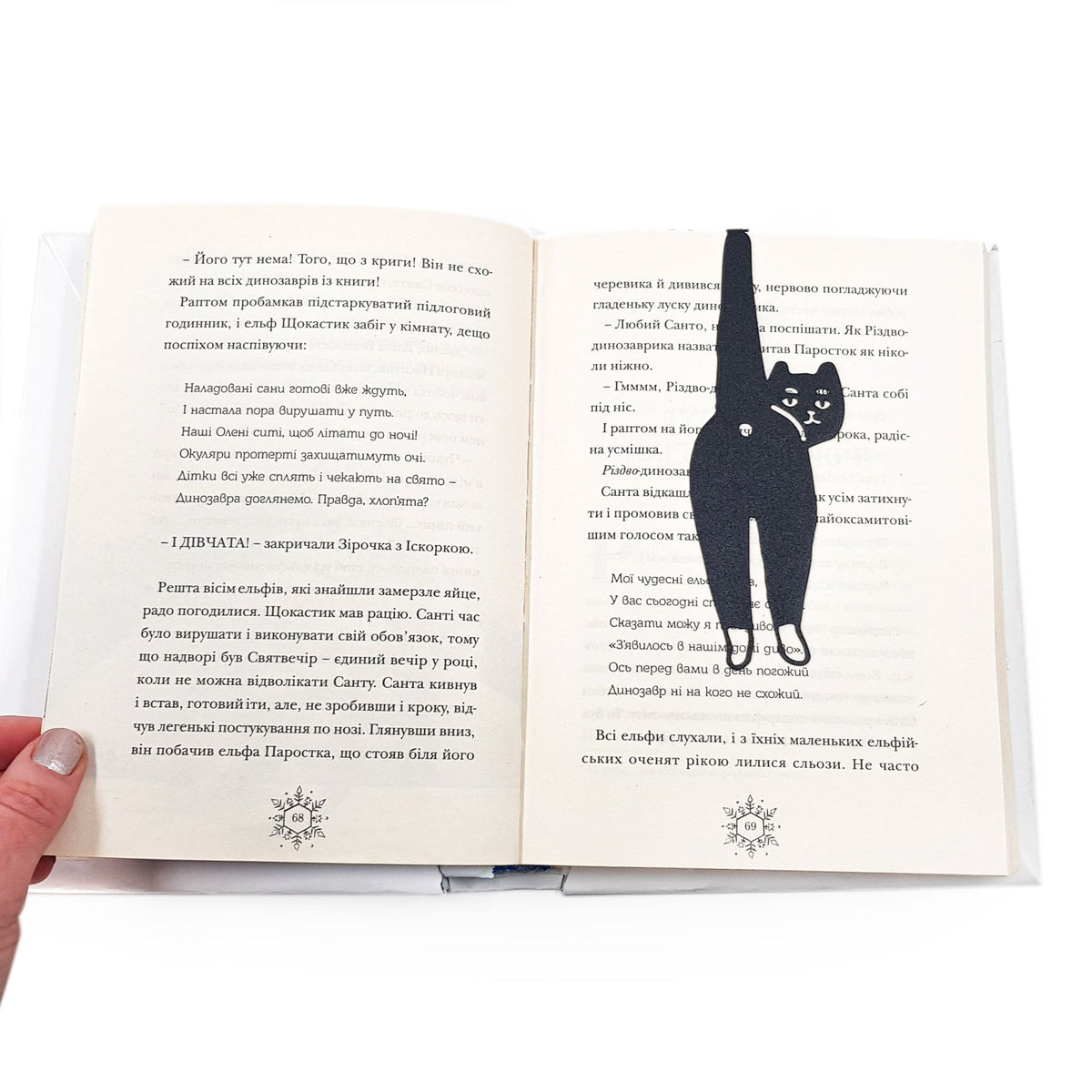 Cheeky Black Cat book marker resting on the pages of an open book