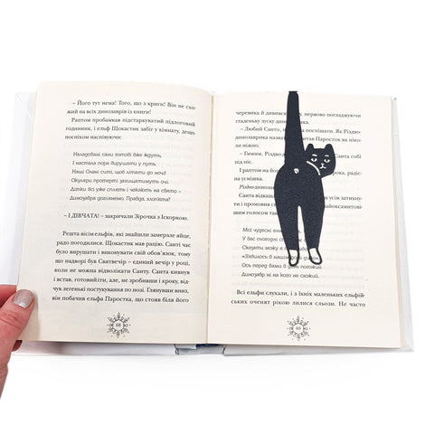 Cheeky Black Cat book marker resting on the pages of an open book