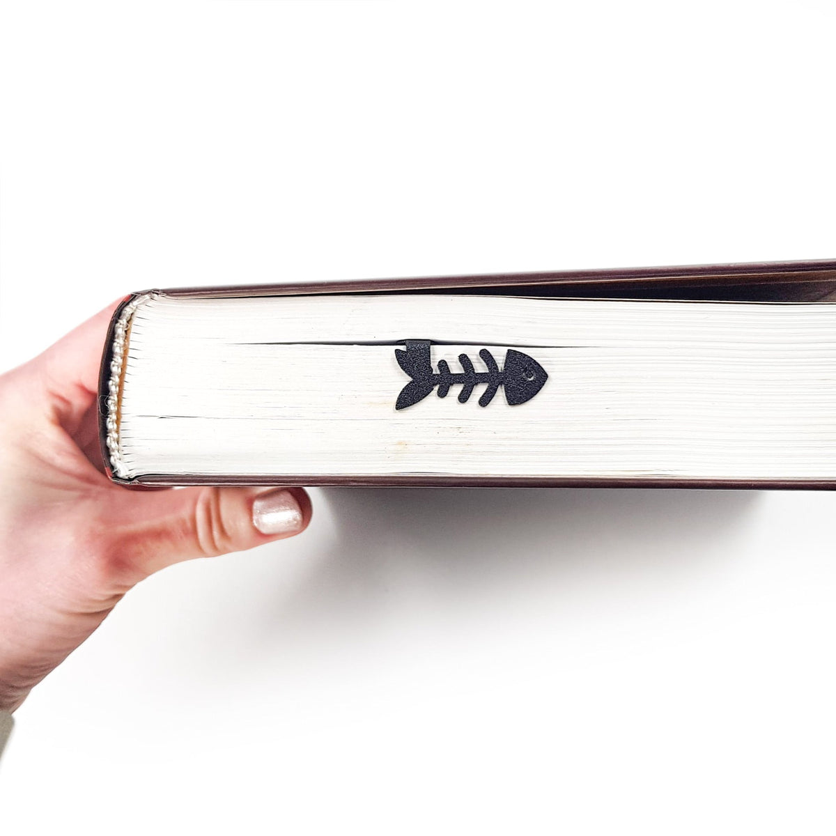 Cheeky Black Cat book marker held in a hand above an open book