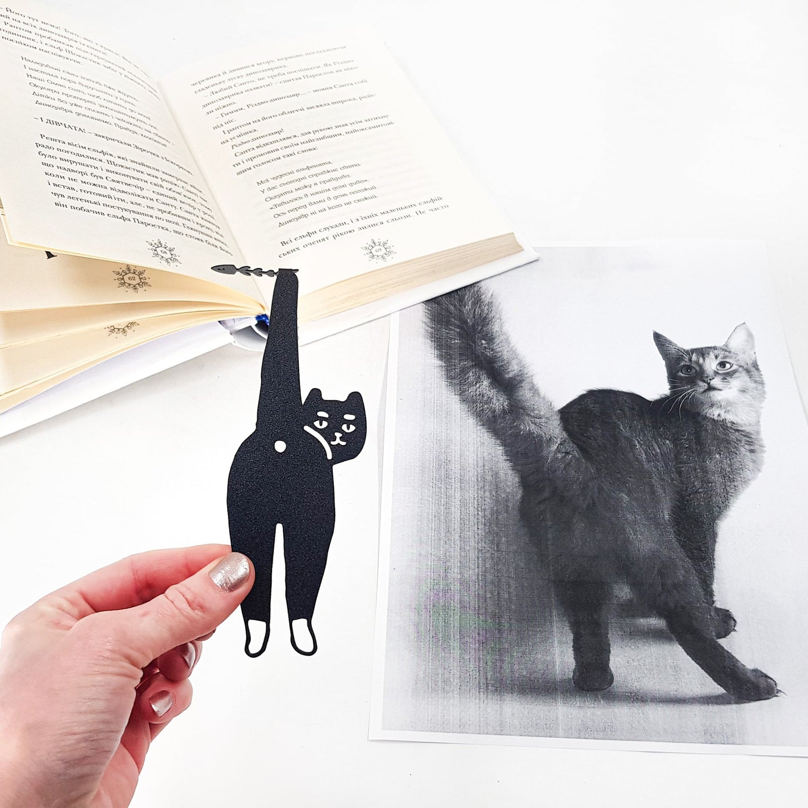 Cheeky Black Cat book marker marking a page in an illustrated book, view 4