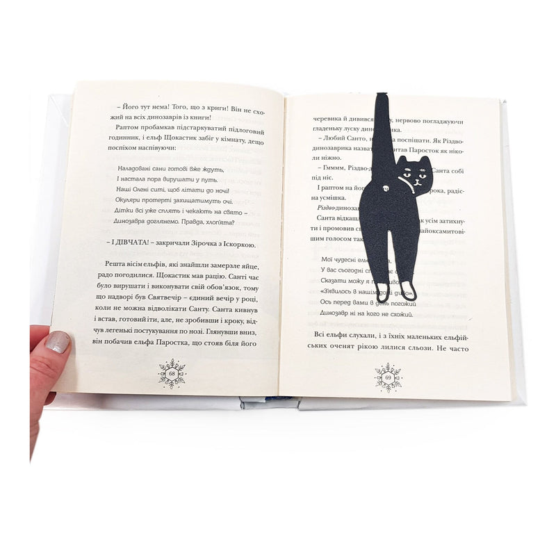 Cheeky Black Cat book marker resting on the pages of an open book
