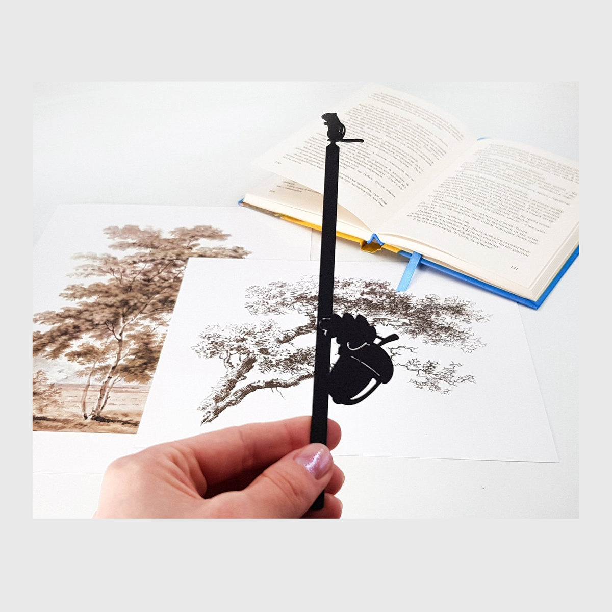 Chipmunk and the Acorn metal bookmark held in a hand above an open book