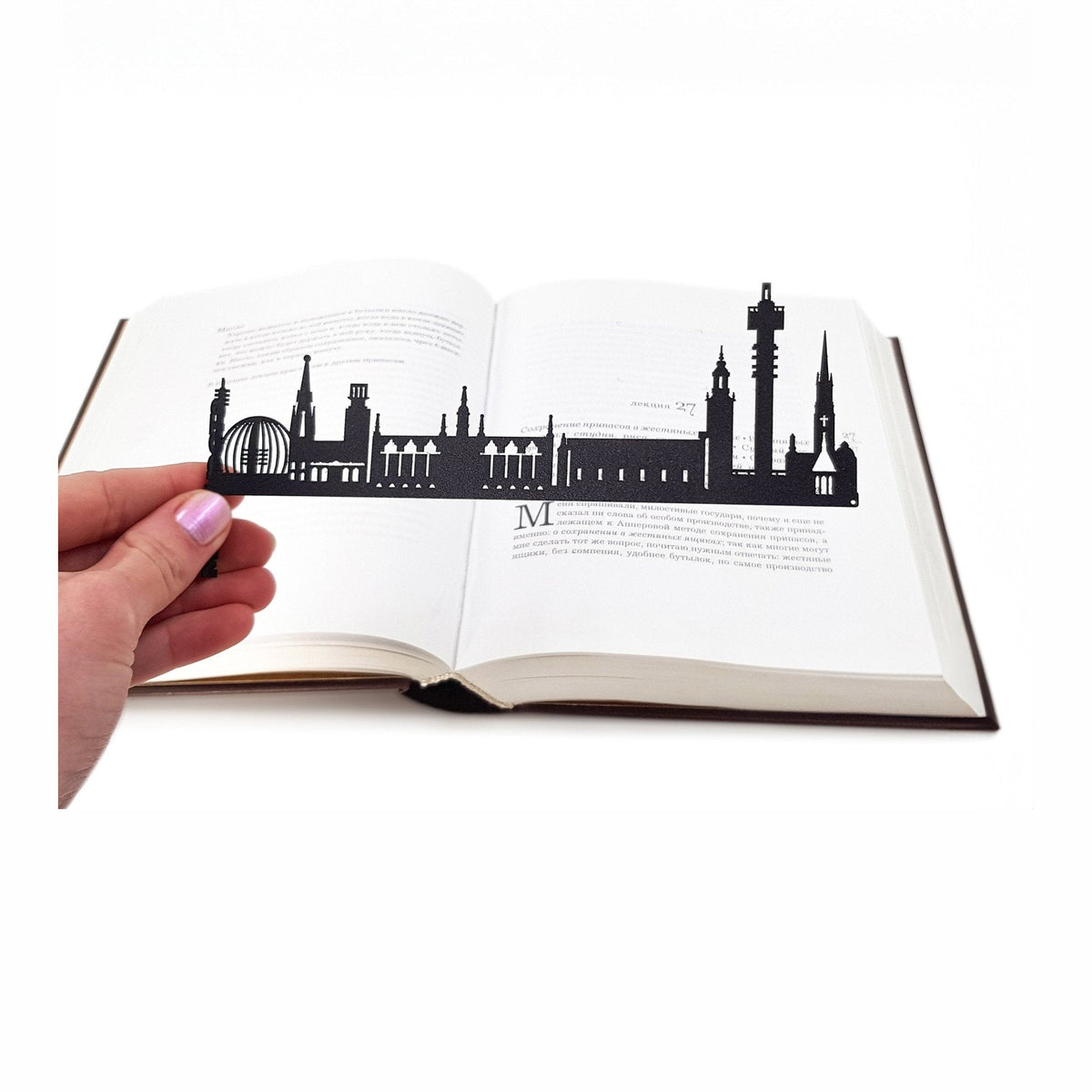 Cityscape Stockholm metal bookmark held in a hand above an open book
