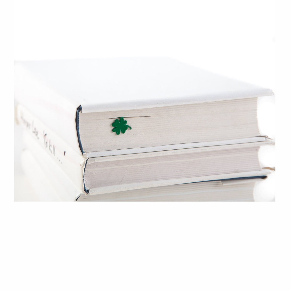 Clover, Good Luck metal bookmark in green in a closed book, only its top showing above the pages