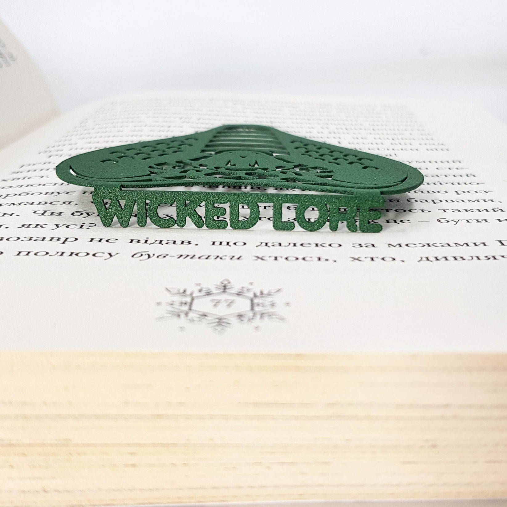 Cobra metal bookmark in green clipped in a closed book, viewed from the side
