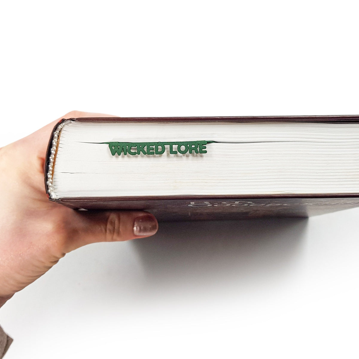Cobra metal bookmark in green in a closed book, only its top showing above the pages