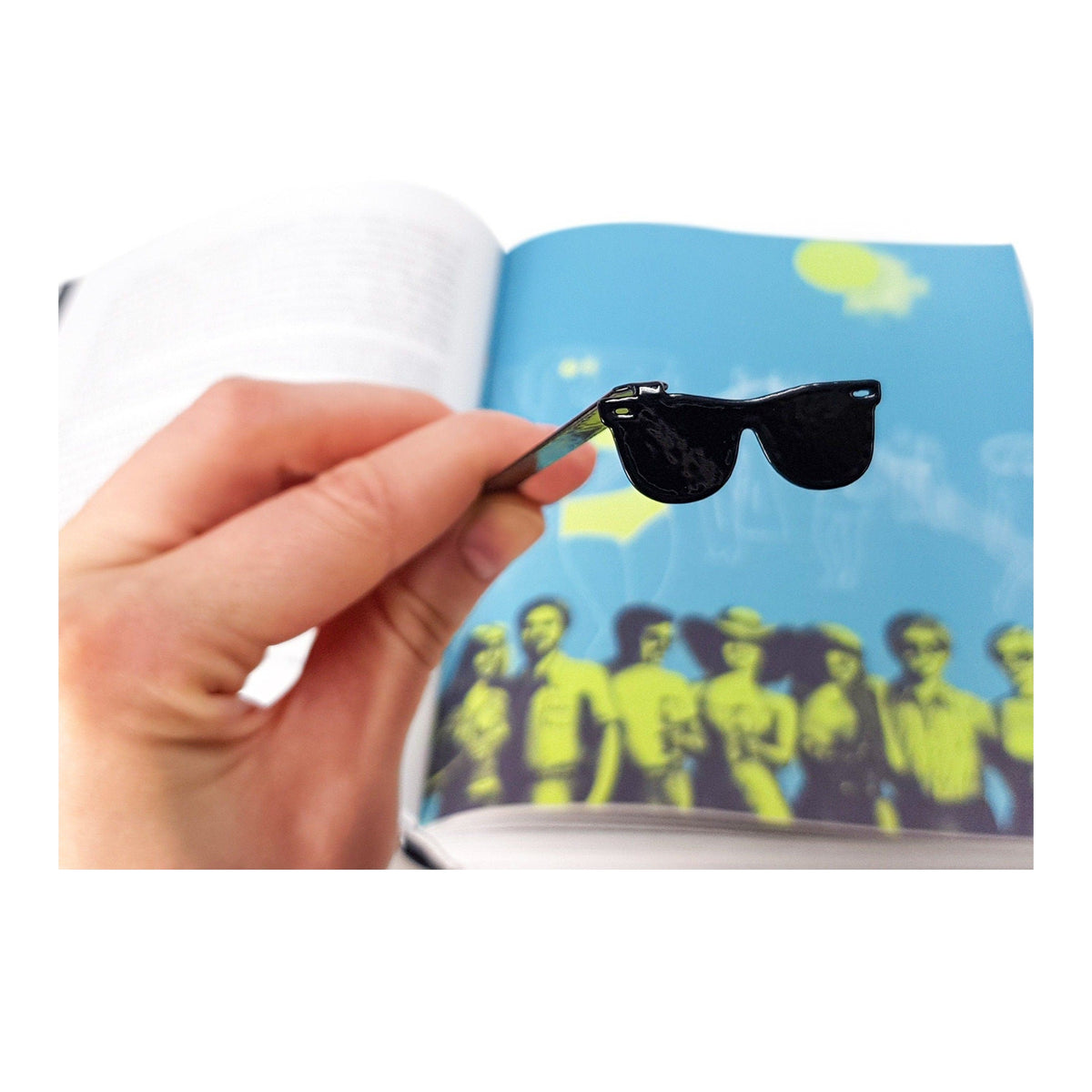 Cool Sunglasses metal bookmark held in a hand above an open book