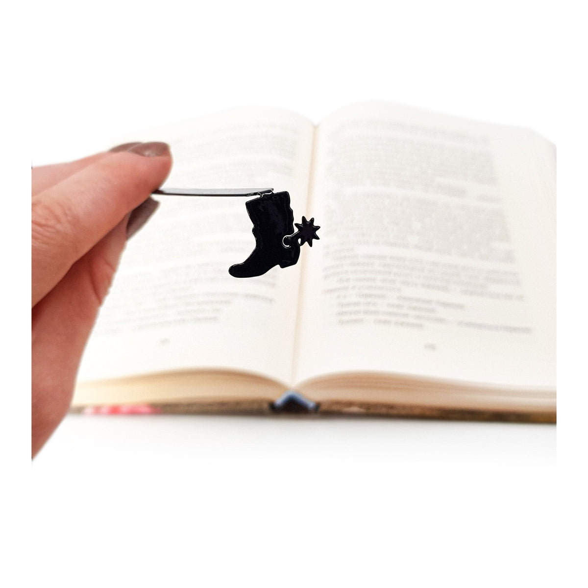Cowboy's Boot metal bookmark held in a hand above an open book
