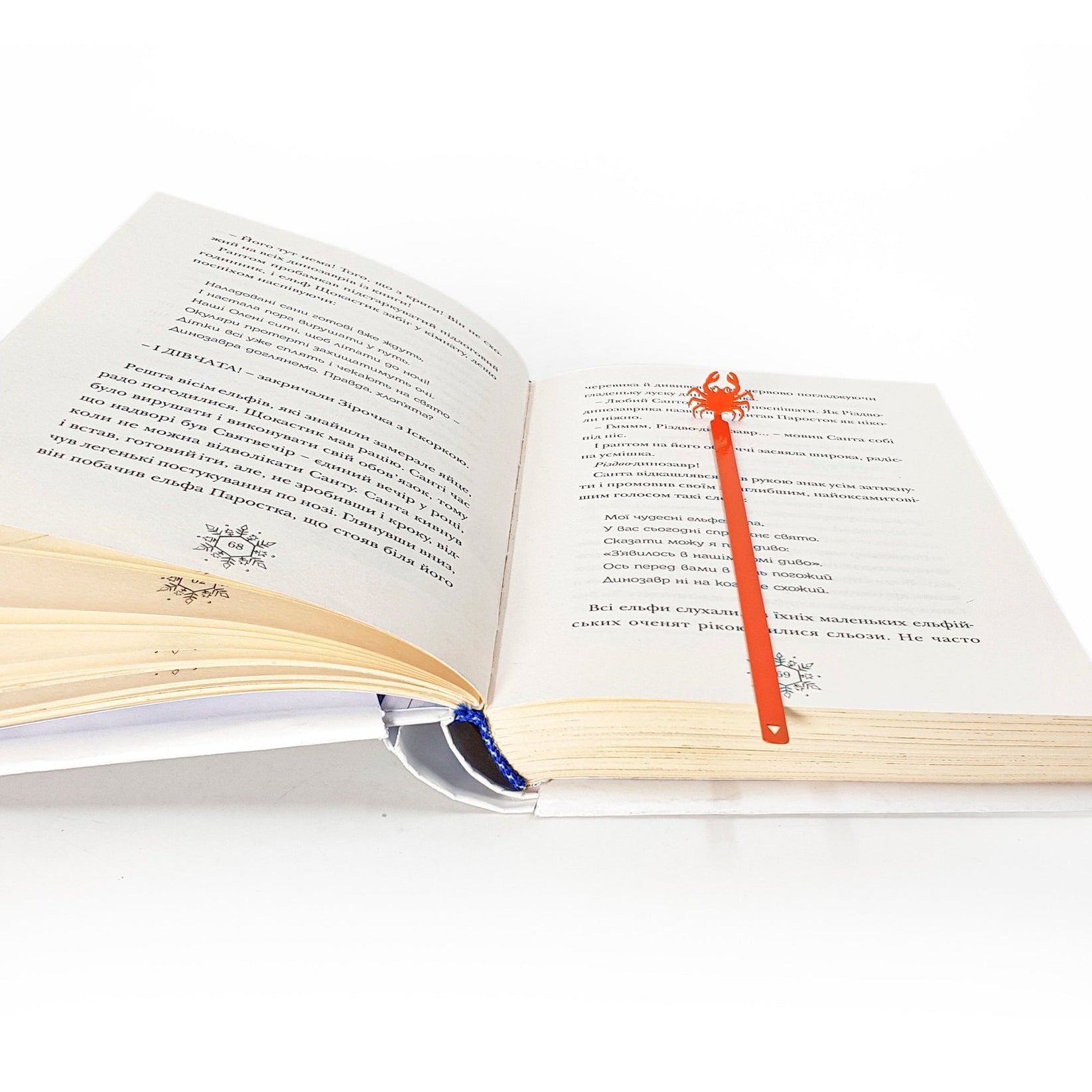 Crab metal bookmark in red marking a page in an open book