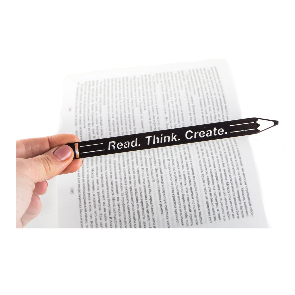 Read. Think. Create. Pencil metal bookmark held in a hand above an open book