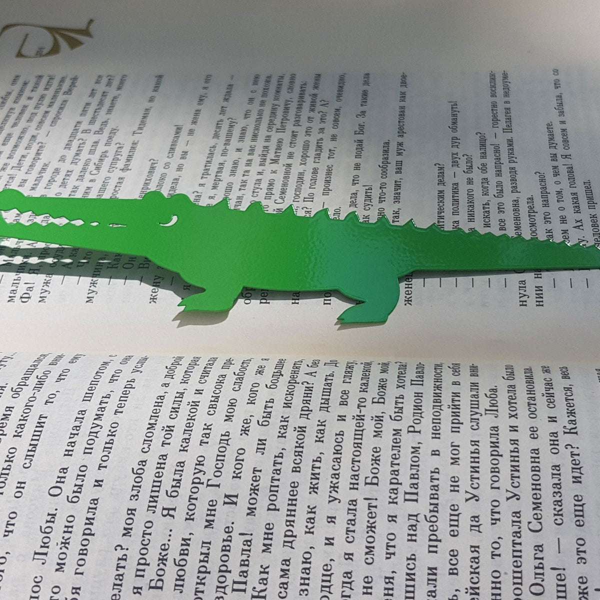 Crocodile and the Nile Bird metal bookmark in green resting on the pages of an open book