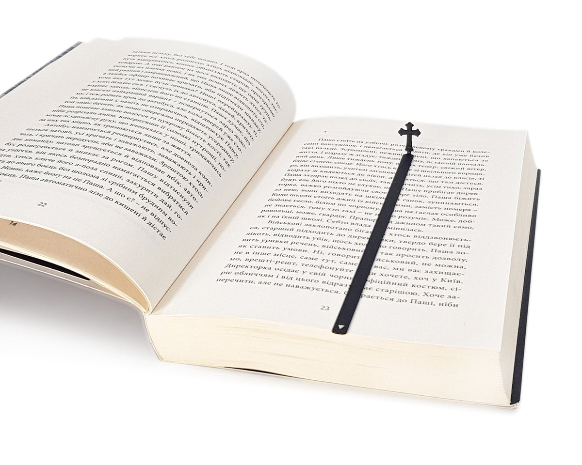 Cross metal bookmark set into the gutter of an open book