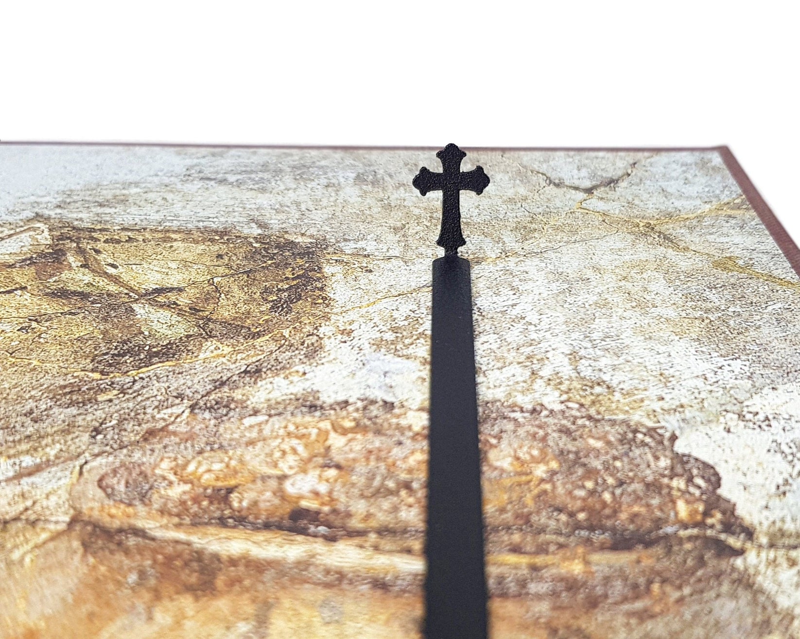 Cross metal bookmark marking a page in an illustrated book