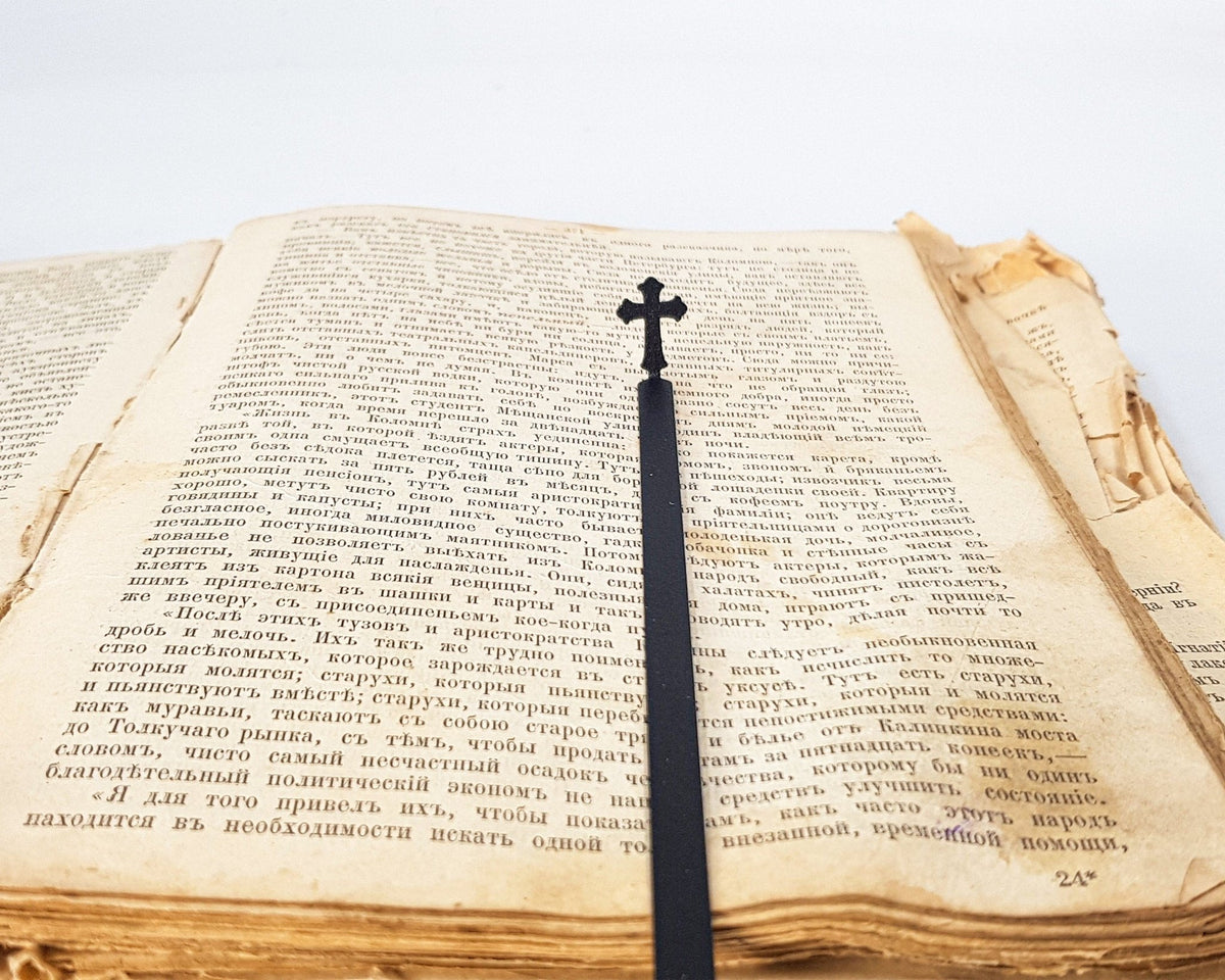 Cross metal bookmark marking a page in an open book