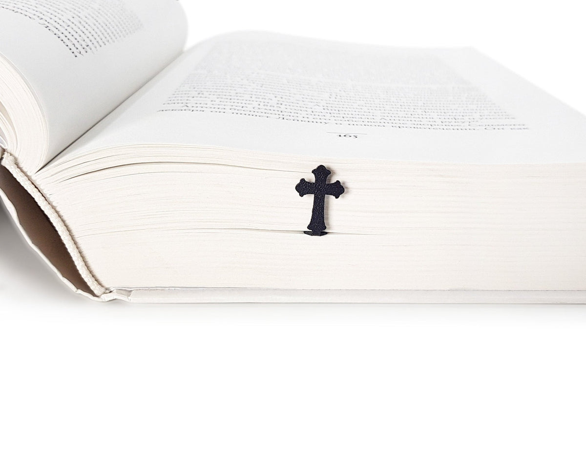 Cross metal bookmark in a closed book, only its top showing above the pages