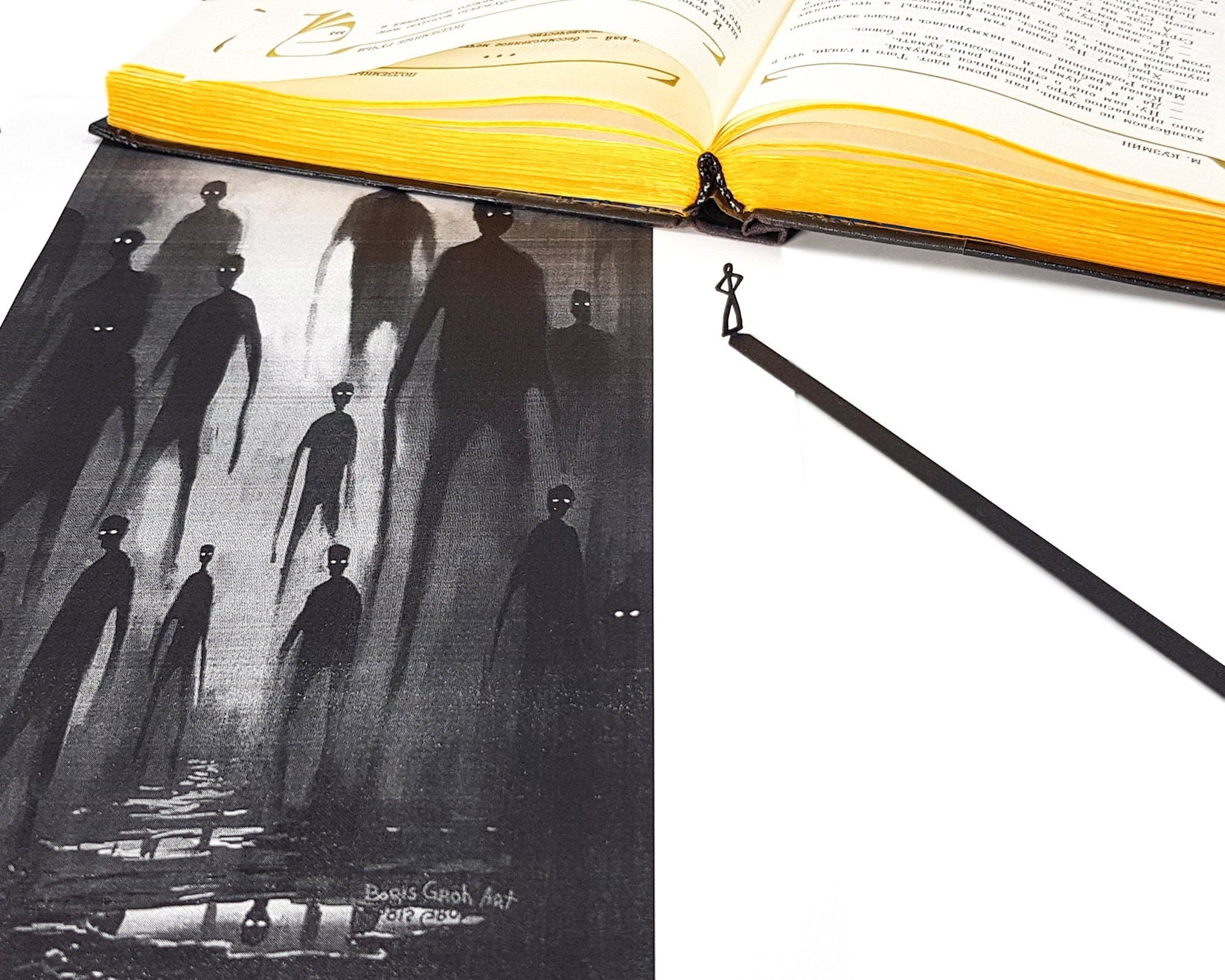 Black Stick Man metal bookmark on an illustrated page