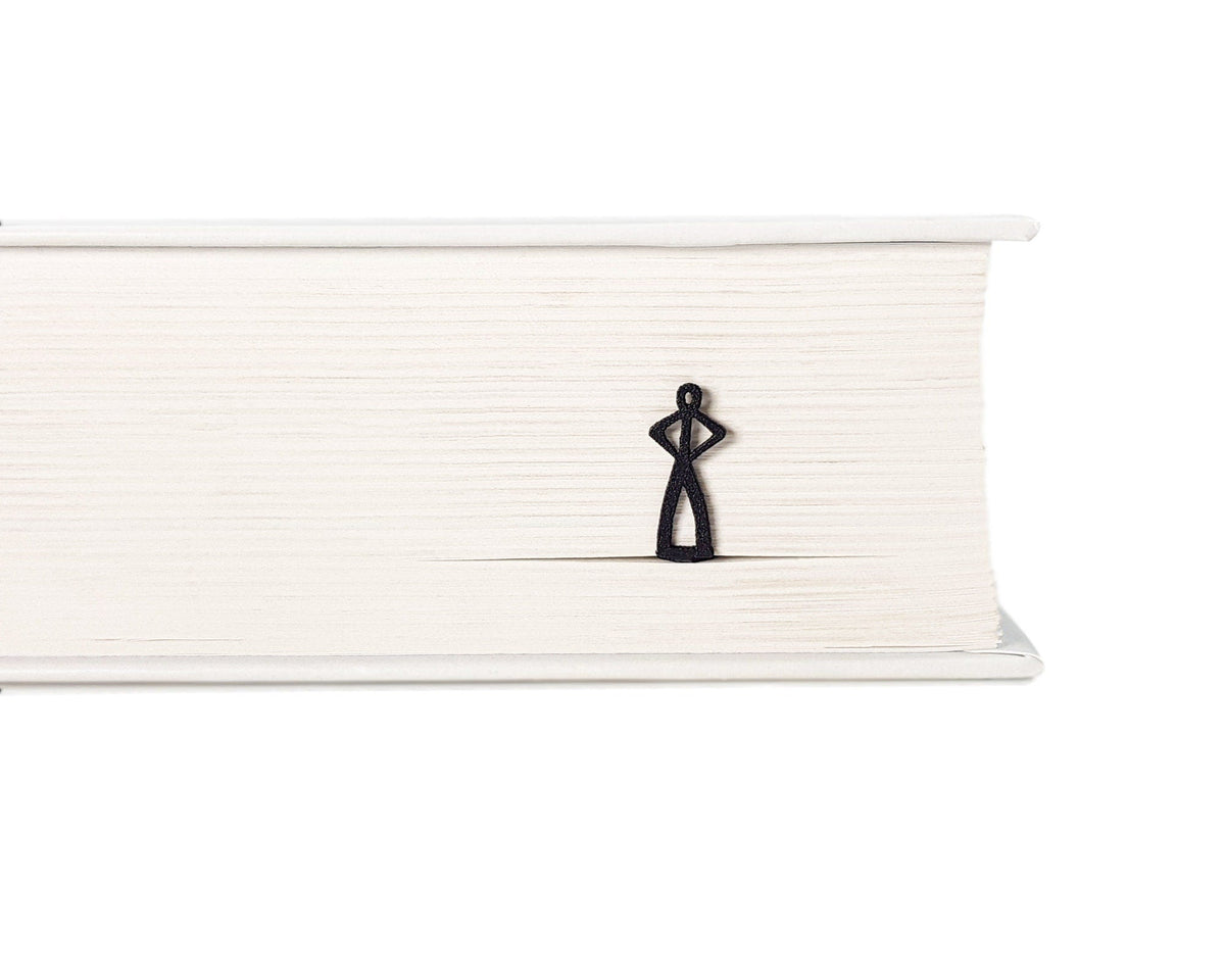 Black Stick Man metal bookmark in a closed book, only its top showing above the pages