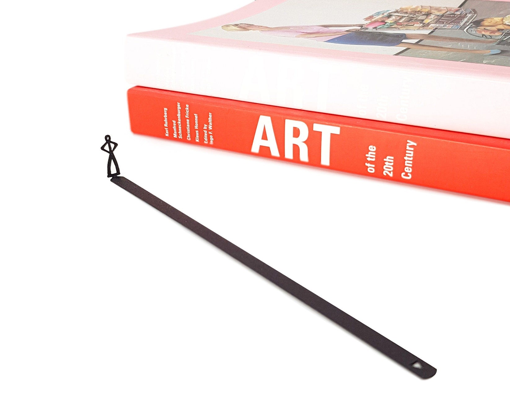 Black Stick Man metal bookmark seen from the edge of a closed book