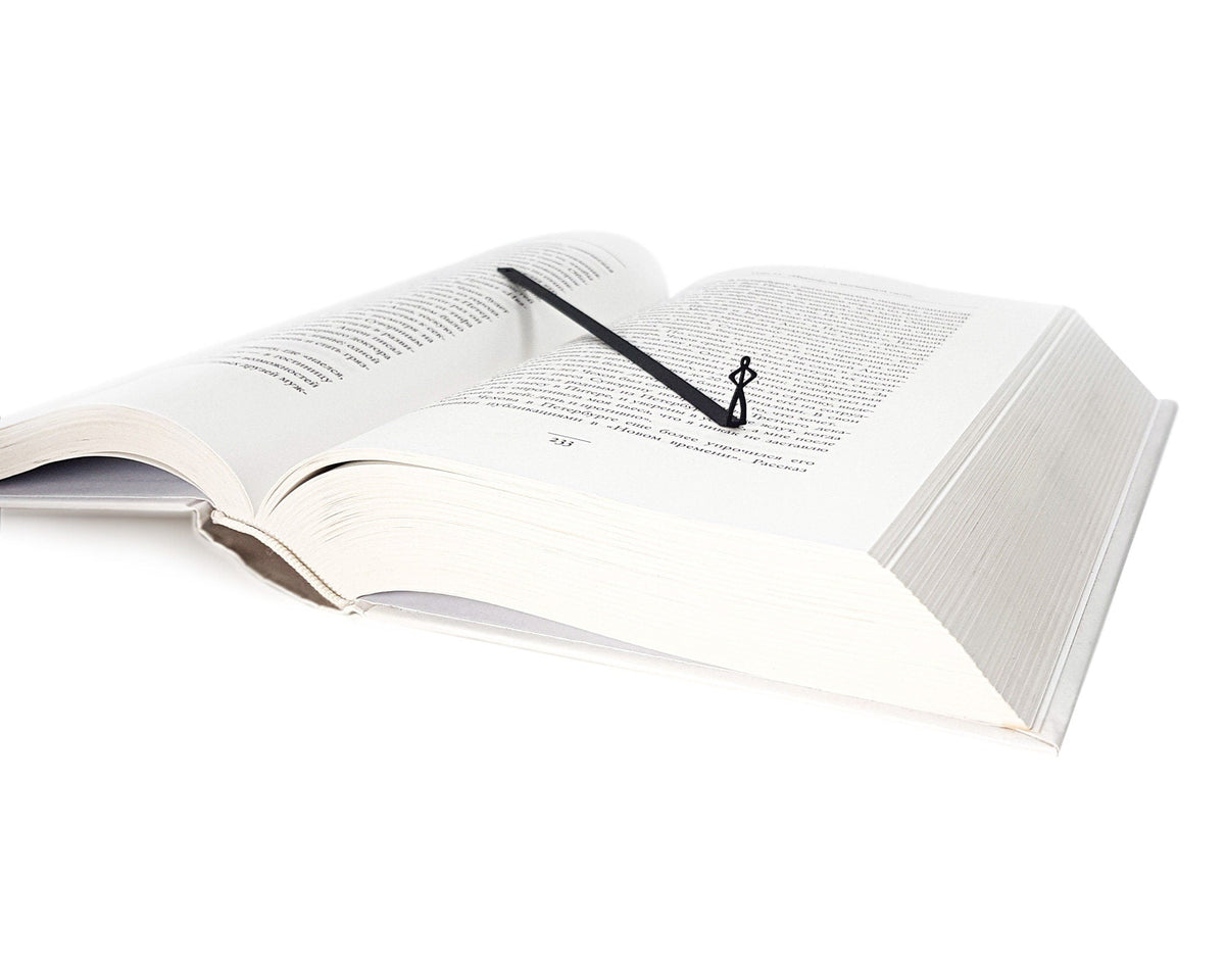 Black Stick Man metal bookmark resting on the pages of an open book