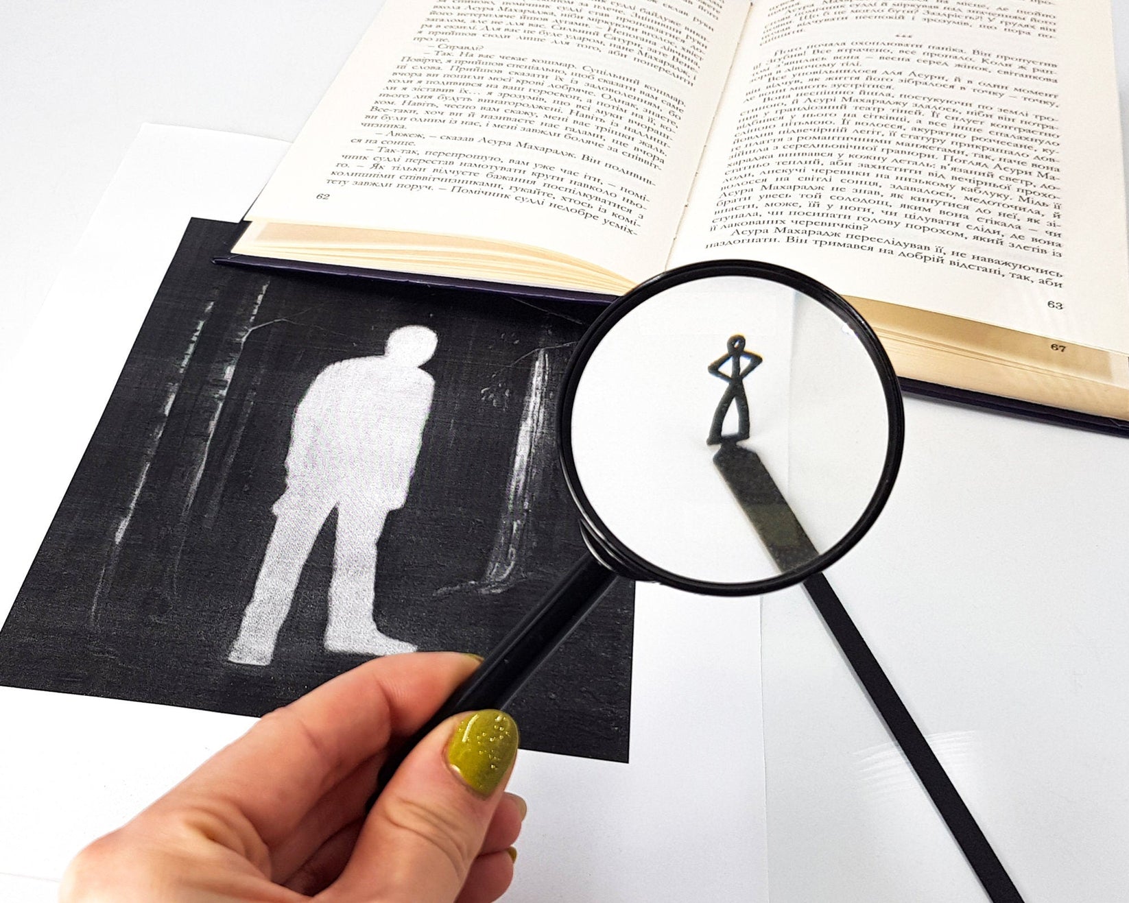 Black Stick Man metal bookmark placed on a colour illustration