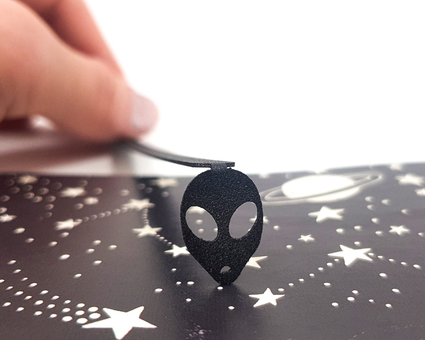 Alien Head metal bookmark on a coloured background