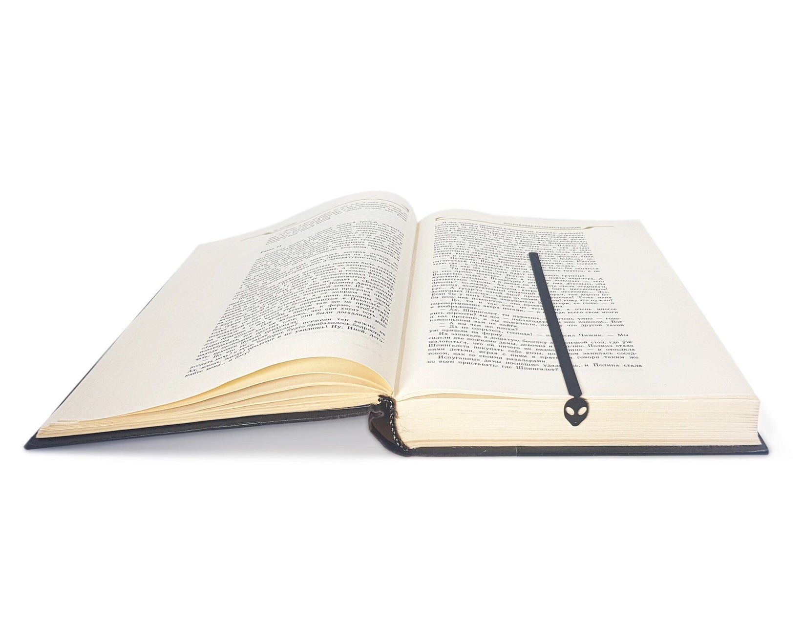 Alien Head metal bookmark marking a page in an open book