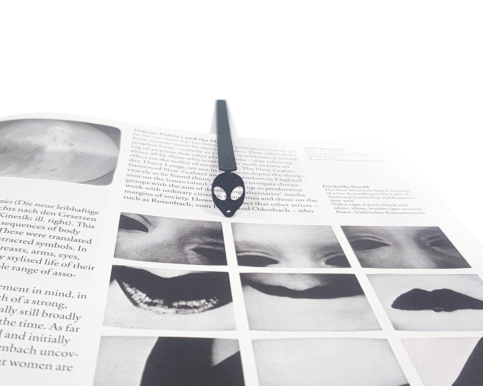 Alien Head metal bookmark marking a page in an illustrated book