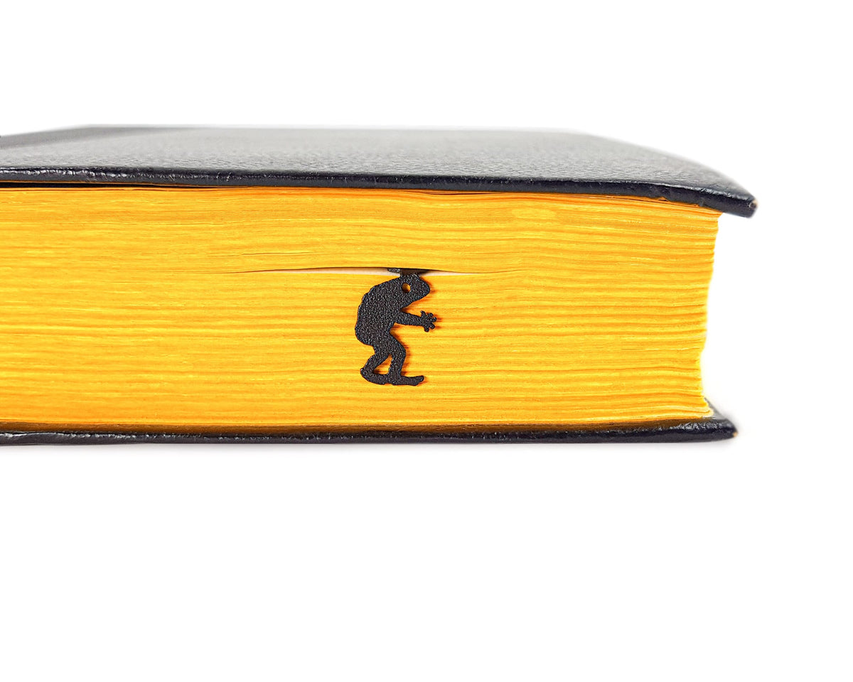Frogman metal bookmark in a closed book, only its top showing above the pages