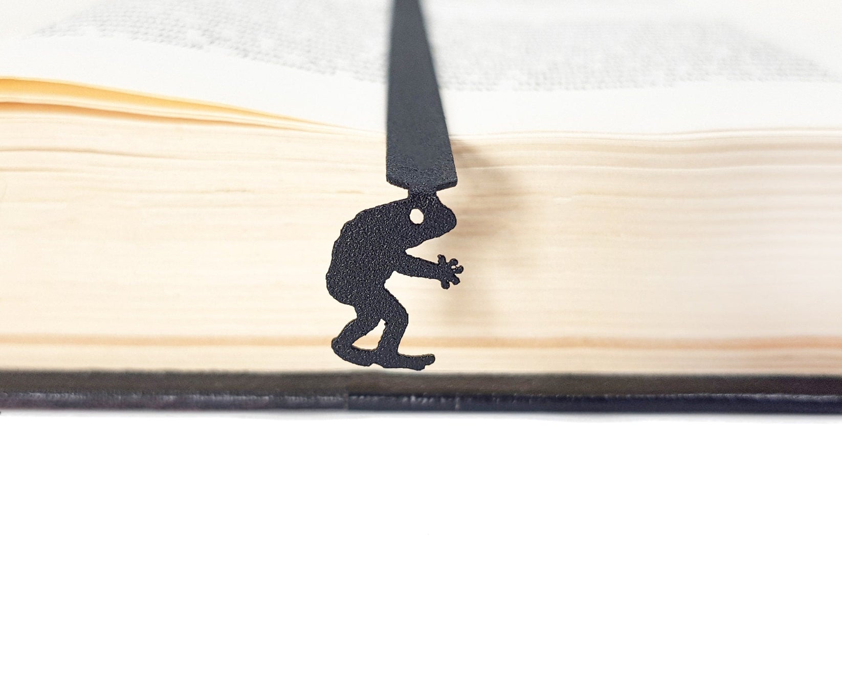 Frogman metal bookmark set into the gutter of an open book