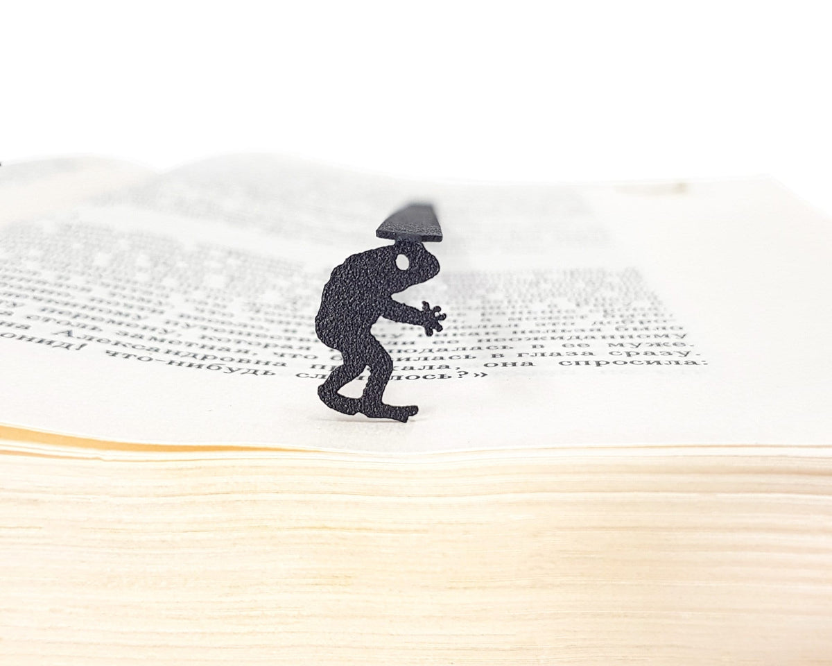 Frogman metal bookmark resting on the pages of an open book