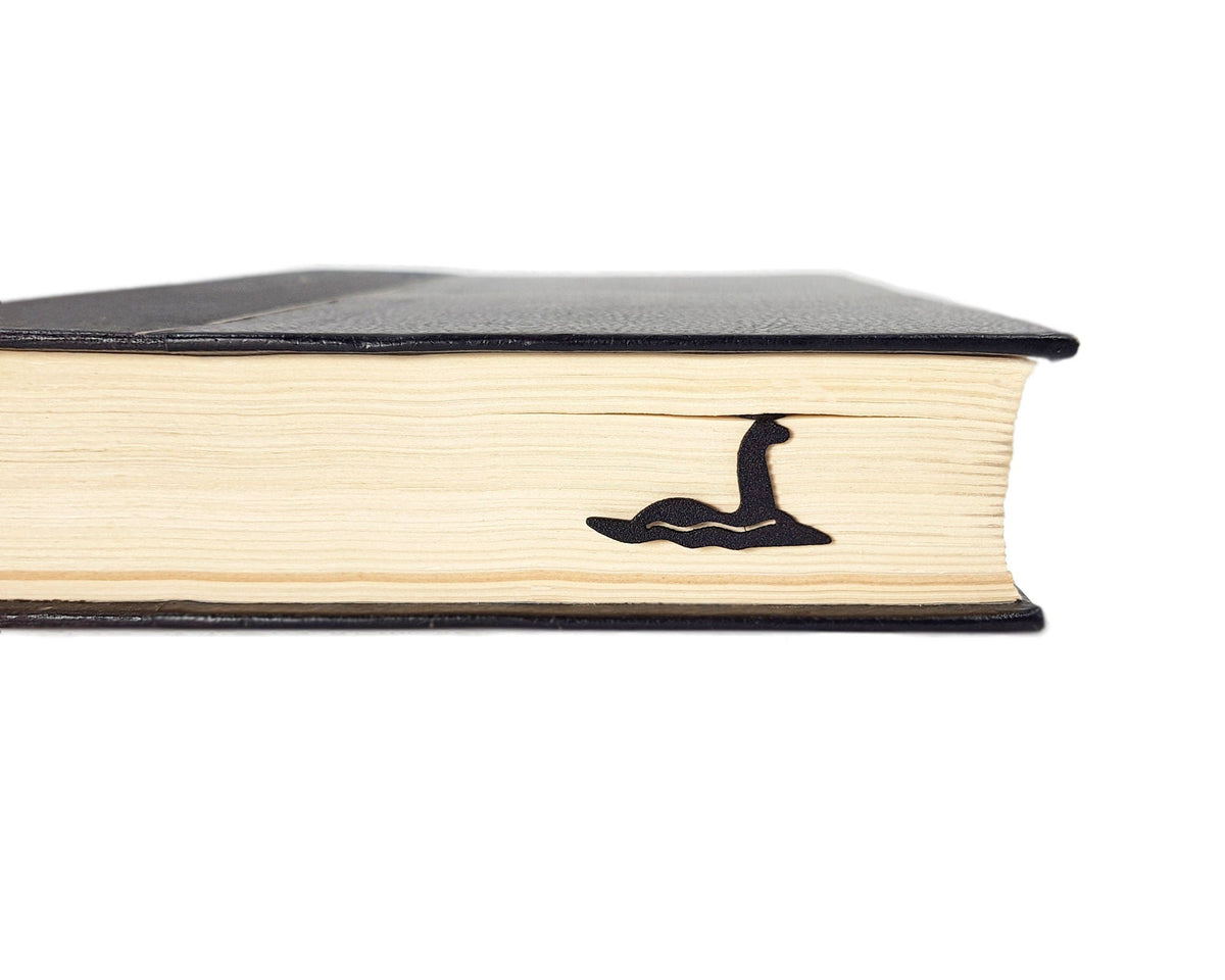 Loch Ness metal bookmark in a closed book, only its top showing above the pages