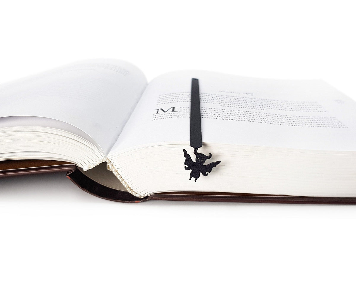 Monster Chupacabra metal bookmark marking a page in an open book