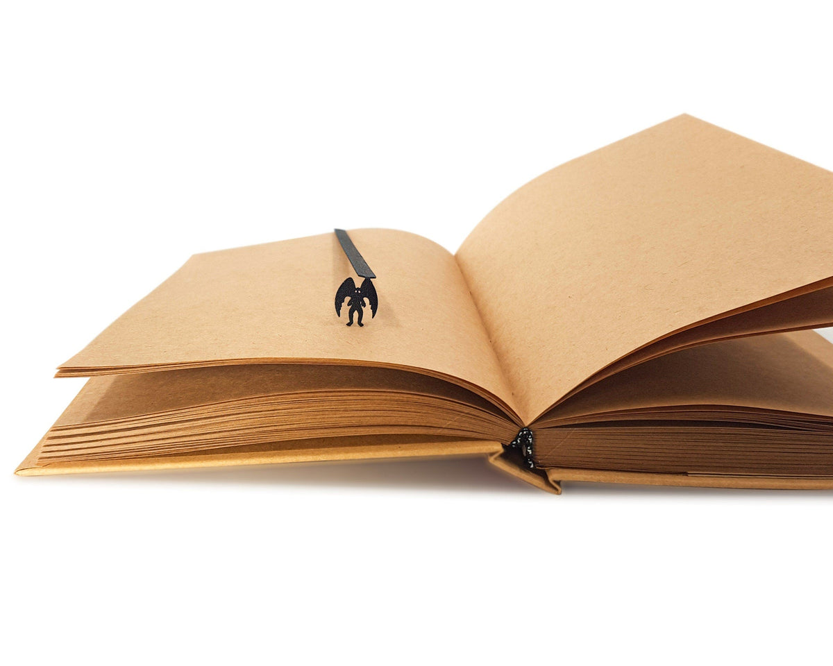Mothman metal bookmark marking a page in an open book