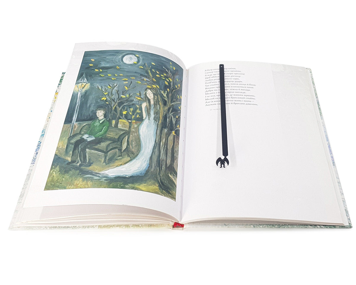Mothman metal bookmark marking a page in an illustrated book
