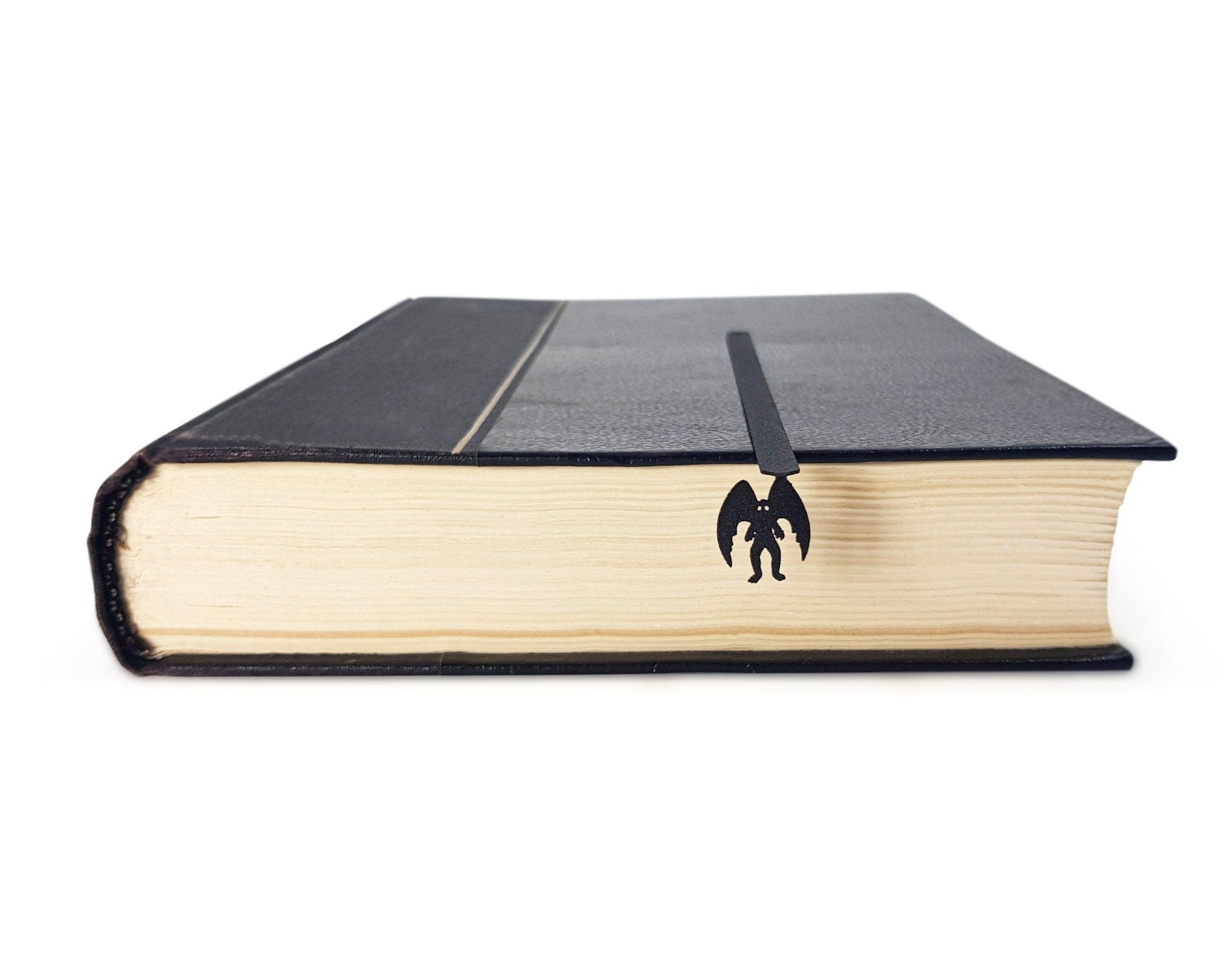 Mothman metal bookmark seen from the edge of a closed book