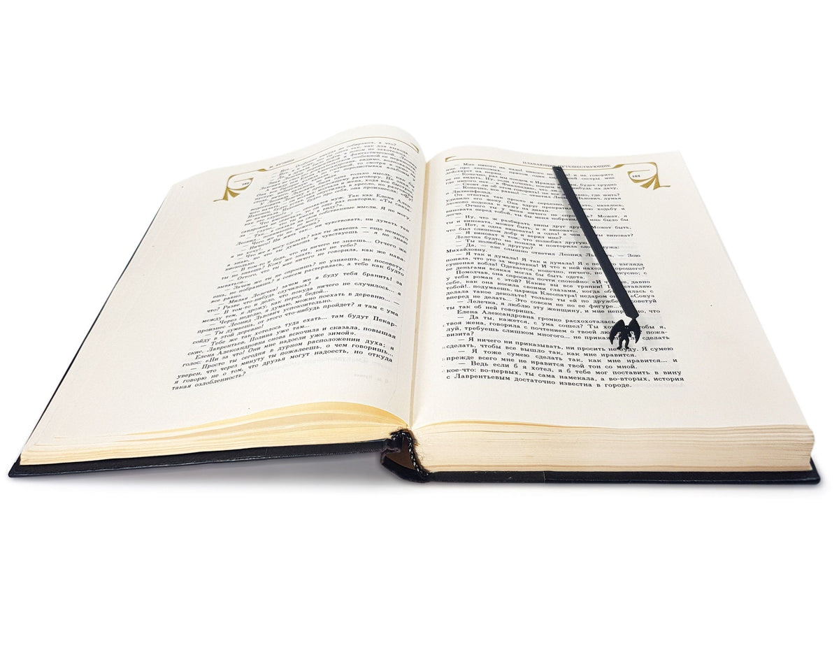 Mothman metal bookmark set into the gutter of an open book